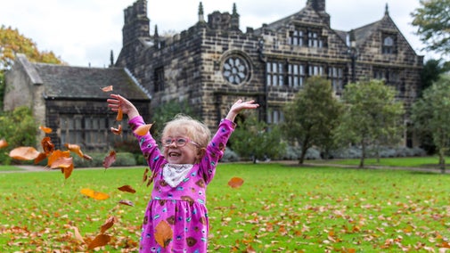 Girl playing in autumn leaves at East Riddlesden Hall, West Yorkshire